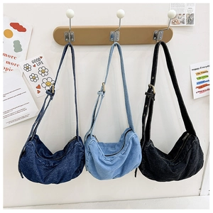 Detailed view of three washed denim hobo bags in dark blue, light blue, and black