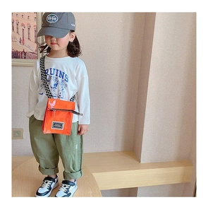 Sac bandoulière enfant en cuir verni orange porté avec une tenue de mode urbaine