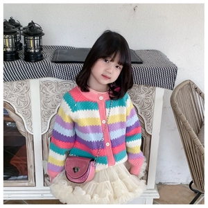 Detailed view of pink sequin heart-lock crossbody bag paired with rainbow knit cardigan