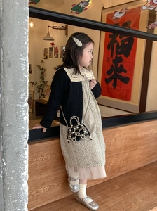 Detail der Mini-Perlenhandtasche für Mädchen mit schwarzer Strickjacke und Blumenkleid