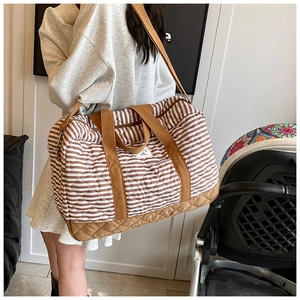 Gros plan du sac à langer rayé matelassé avec texture et bandoulière marron robuste