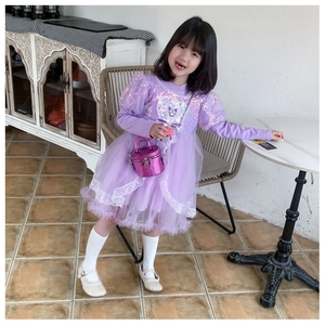 Détail d'un enfant portant une robe à paillettes violette et un petit sac assorti
