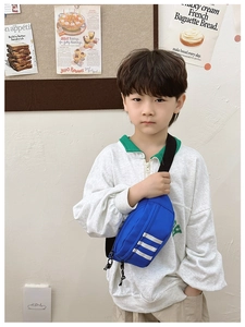 Close-up of blue kids crossbody bag with white stripes on a fabric texture material