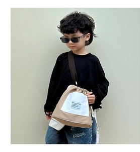 Detail of khaki drawstring kids canvas bag with adjustable strap and front pocket