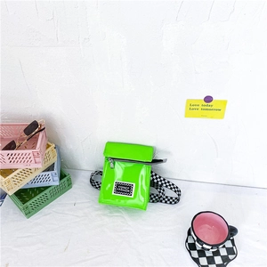 Détail du mini sac en cuir verni vert néon avec bandoulière à carreaux sur tissu