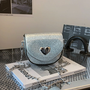 Detail of silver sequin mini bag featuring a heart-shaped metal twist lock and chain strap