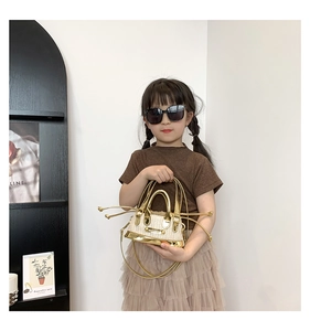 Détail d'un mini sac en paille pour enfant avec garniture et poignée en cuir doré brillant