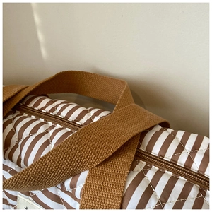 Détail du sac cabas rayé matelassé montrant la bandoulière marron et le zip en métal