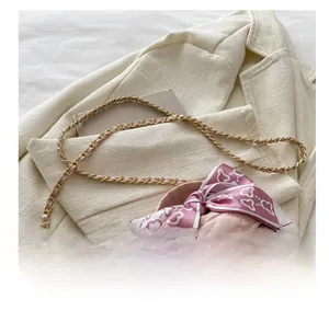 Gros plan d'un mini sac matelassé rose avec nœud en soie et bandoulière dorée