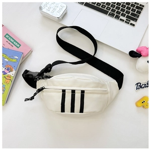 Detail view of white canvas crossbody bag with black stripes on a lifestyle desk setup