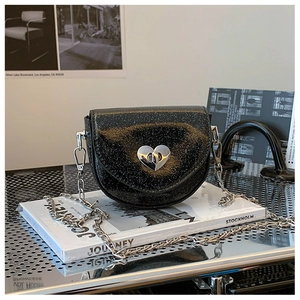 Detail of black glitter crossbody bag featuring a silver heart-shaped twist lock buckle