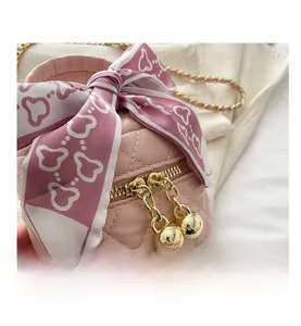 Détail du sac seau rose matelassé avec nœud en soie et fermetures éclair boules dorées