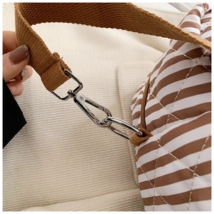 Détail du fermoir mousqueton en métal argenté et de la bandoulière de sac matelassé