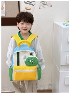 Detail of color-block kids backpack with cute cartoon pendant and durable canvas texture