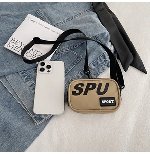 Dettaglio di una mini borsa a tracolla in tela con scritta SPU su sfondo denim