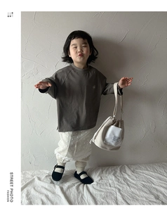 Kids cream canvas drawstring bucket bag styled with gray sweatshirt and lace skirt