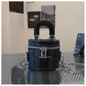 Détail du mini sac seau à paillettes noires avec chaîne argentée sur fond métal