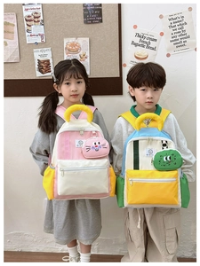 Detail of color-block kids backpack with cute cartoon pendant and durable nylon fabric