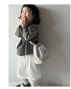 Detail view of beige canvas drawstring bucket bag with decorative side pocket for kids