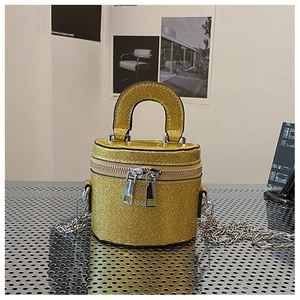 Détail d'un mini sac seau cylindrique doré pailleté avec une bandoulière en chaîne