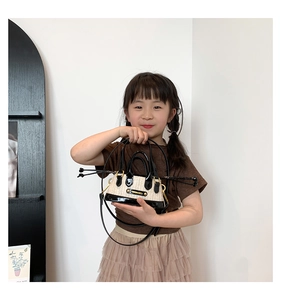 Détail du mini sac bandoulière enfant en paille avec bordure en cuir verni noir et plaque