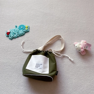 Detail view of army green canvas drawstring bag featuring a white pocket with bold slogan