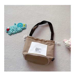 Detail of khaki canvas drawstring crossbody bag with large woven label and adjustable strap