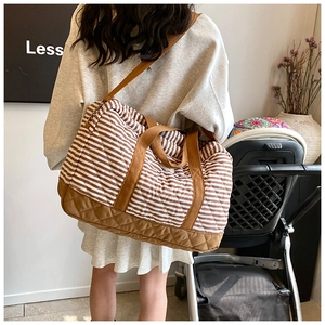 Détail du sac à langer rayé matelassé avec poignées marron renforcées et coutures