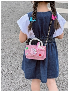 Detail of pink sequin girl's purse with pearl handle and mermaid tail on a child model