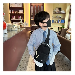 Detail of a black nylon kids chest bag featuring FASHION text and lettered straps