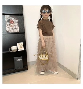 Détail d'un haut en tricot marron pour fille avec jupe en tulle rose et sac doré élégant