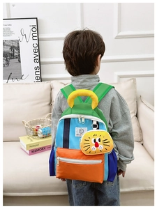 Detailed view of kids color-block backpack with cute lion pendant and carry handle