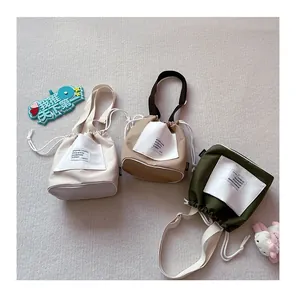Detail of canvas drawstring bucket bags in beige, khaki and dark green with strap