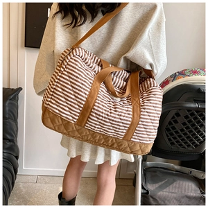 Détail d'un grand sac à langer en toile rayée marron avec fond matelassé et bandoulière