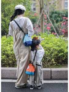 Outdoor shot showing adult and child wearing color-block drawstring nylon bucket bags