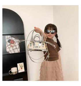 Détail d'un mini sac en paille pour enfant avec bordure en cuir argenté et logo en métal
