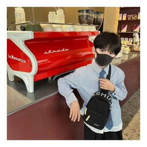 Detail of kids black chest bag with white FASHION lettering and yellow zipper puller