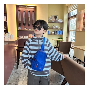 Close-up of blue nylon crossbody chest bag for kids with orange CH logo and fashion detail