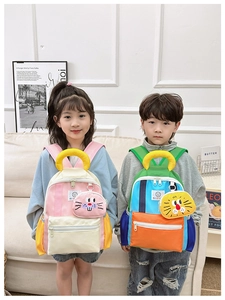 Detail of color-block kids backpacks featuring detachable cartoon animal pendant charms