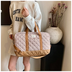Détail du sac de voyage matelassé à carreaux avec bandoulière dans un décor décontracté