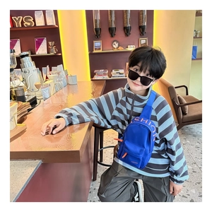 Close-up of kids blue nylon chest bag with orange fashion lettering and zipper detail