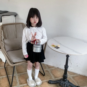 Fille en t-shirt lapin blanc et jupe plissée noire avec un sac à seaux pailleté argent
