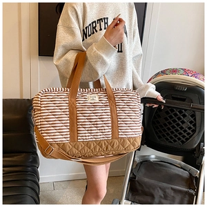 Sac à langer matelassé à rayures avec base renforcée et bandoulière près d'une poussette