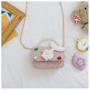 Detail of pink sequin girl's purse with pearl handle and fish tail decor on white cloth