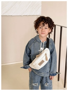 Détail d'un sac banane en toile blanche avec sangle réglable sur un sweat à capuche denim
