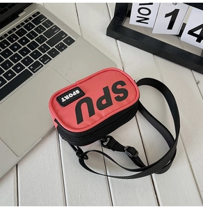 Dettaglio mini borsa a tracolla rosa in tela con scritte sport su legno bianco