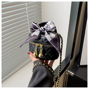 Détail d'un sac seau noir matelassé avec fermetures dorées et ruban de soie élégant