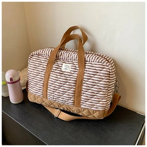 Détail du sac de voyage matelassé à rayures brunes avec poignées en toile robustes