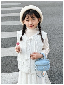 Close-up of a child wearing a quilted vest and a blue denim chain crossbody bag