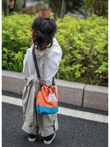 Detail of color-block kids crossbody bucket bag with drawstring closure and strap